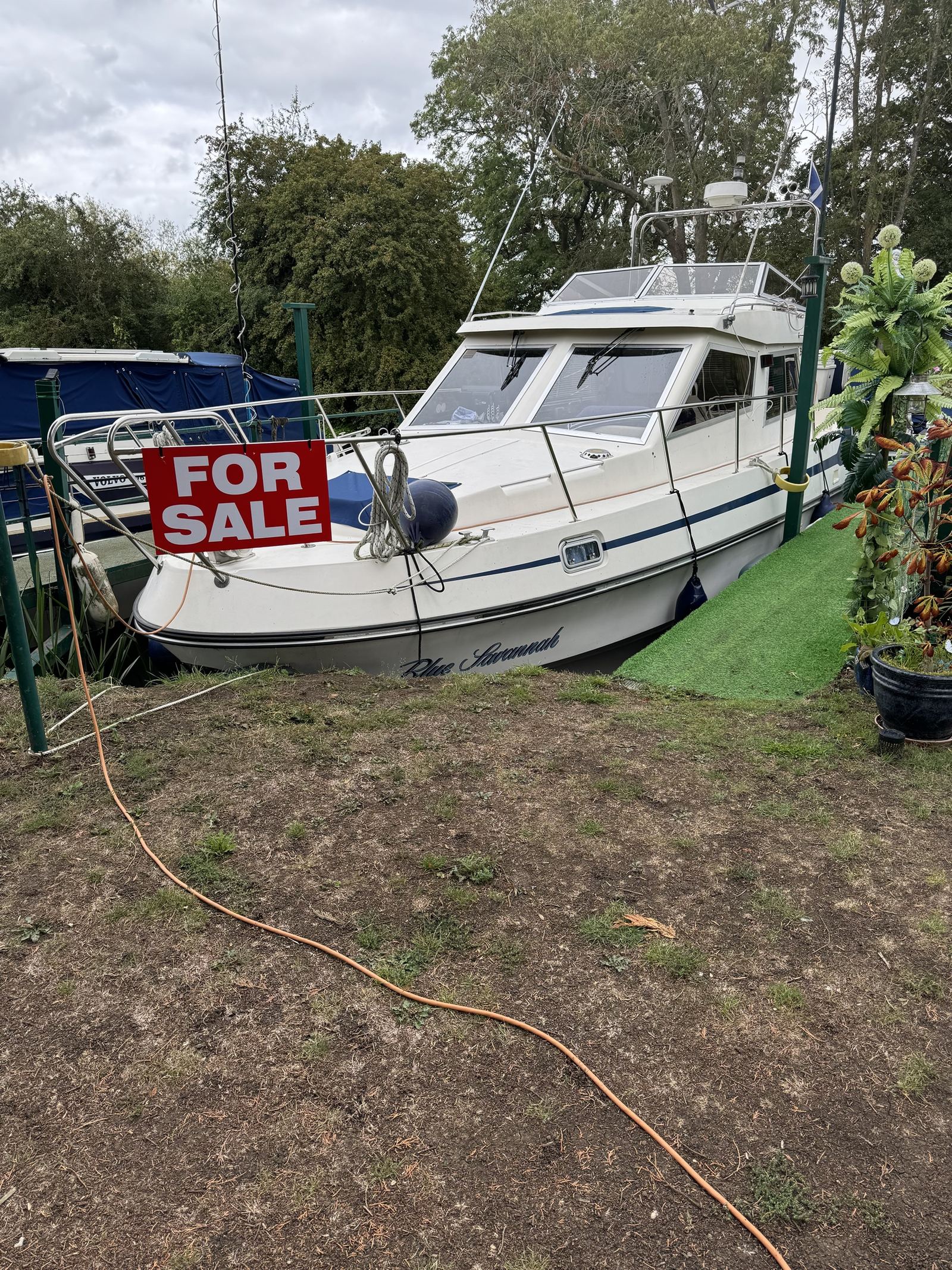 Blue Savannah, a twin-engine flybridge cruiser, moored at Strensham Mill with a for sale sign on the guard rail.